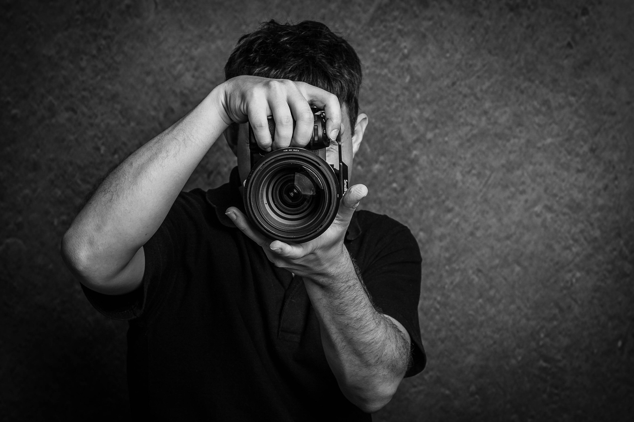Black and white portrait of Ben looking through the lens of his camera