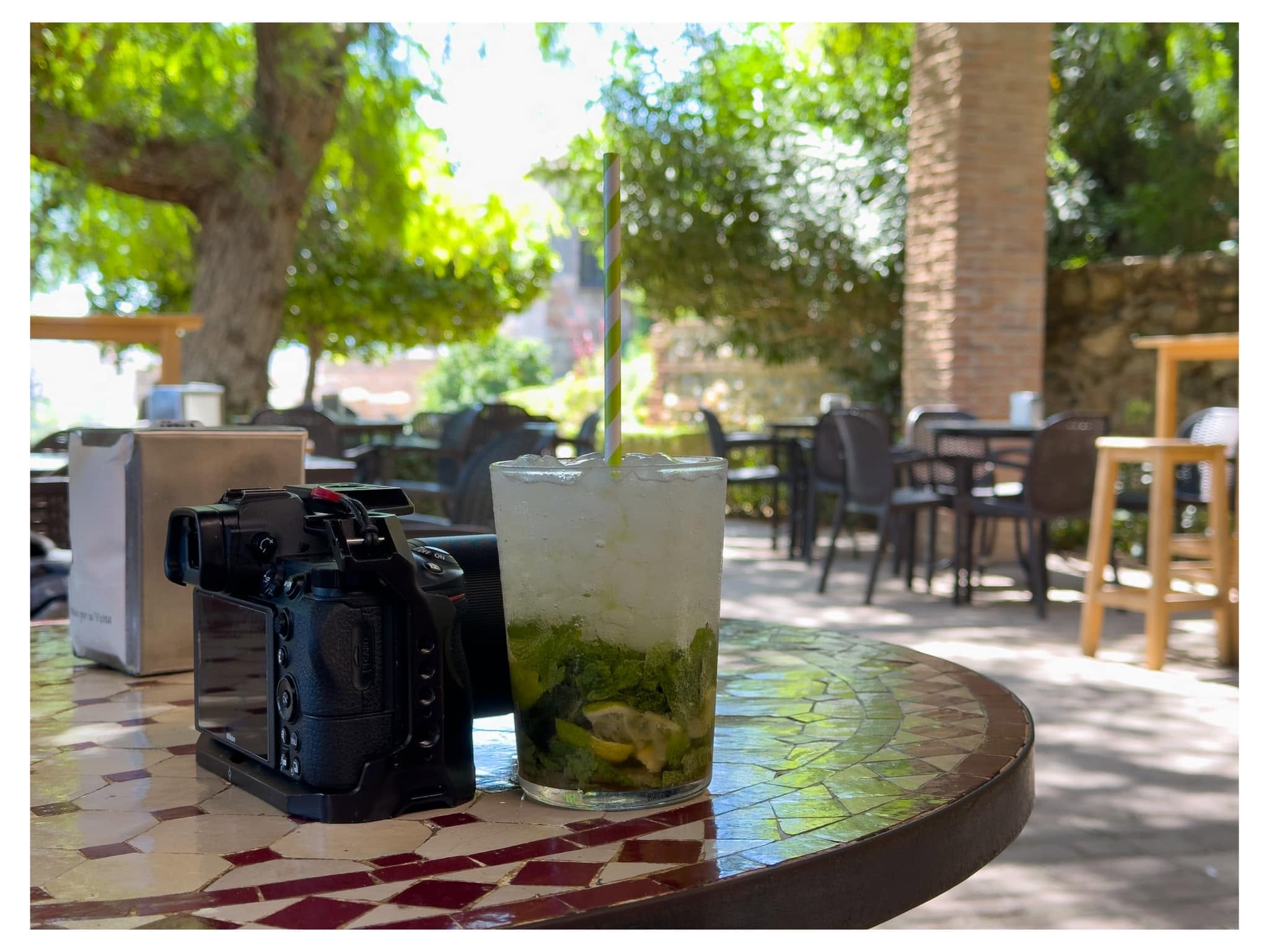 Camera and iced drink on a sunlit café table outdoors