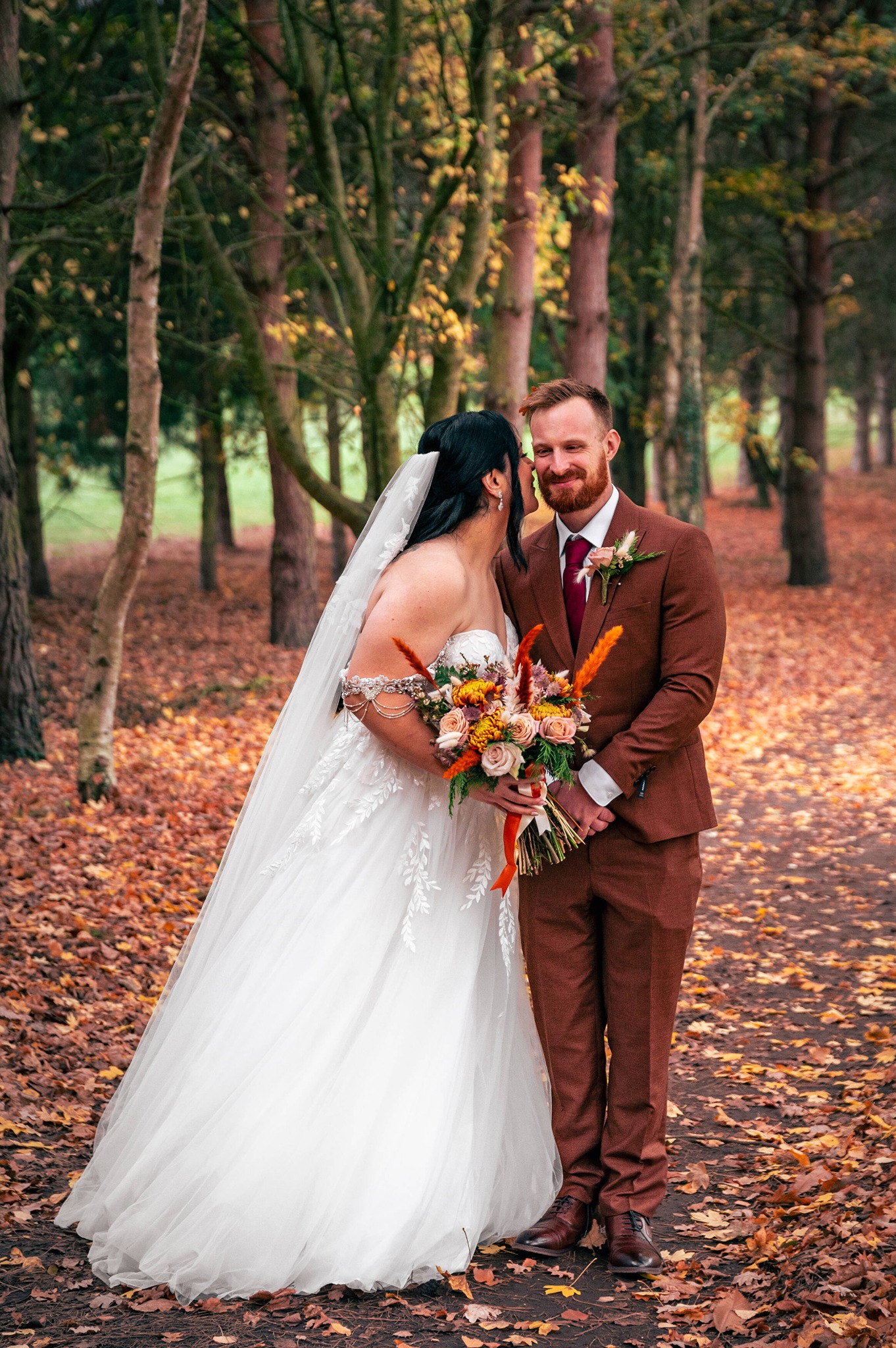 A newly married couple standing together among autumn trees