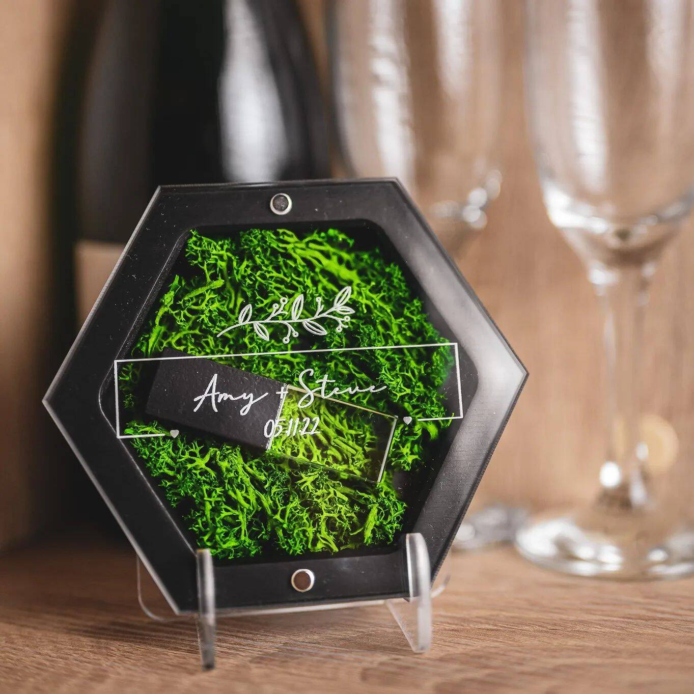 Wedding rings displayed in a geometric glass ring box with green moss