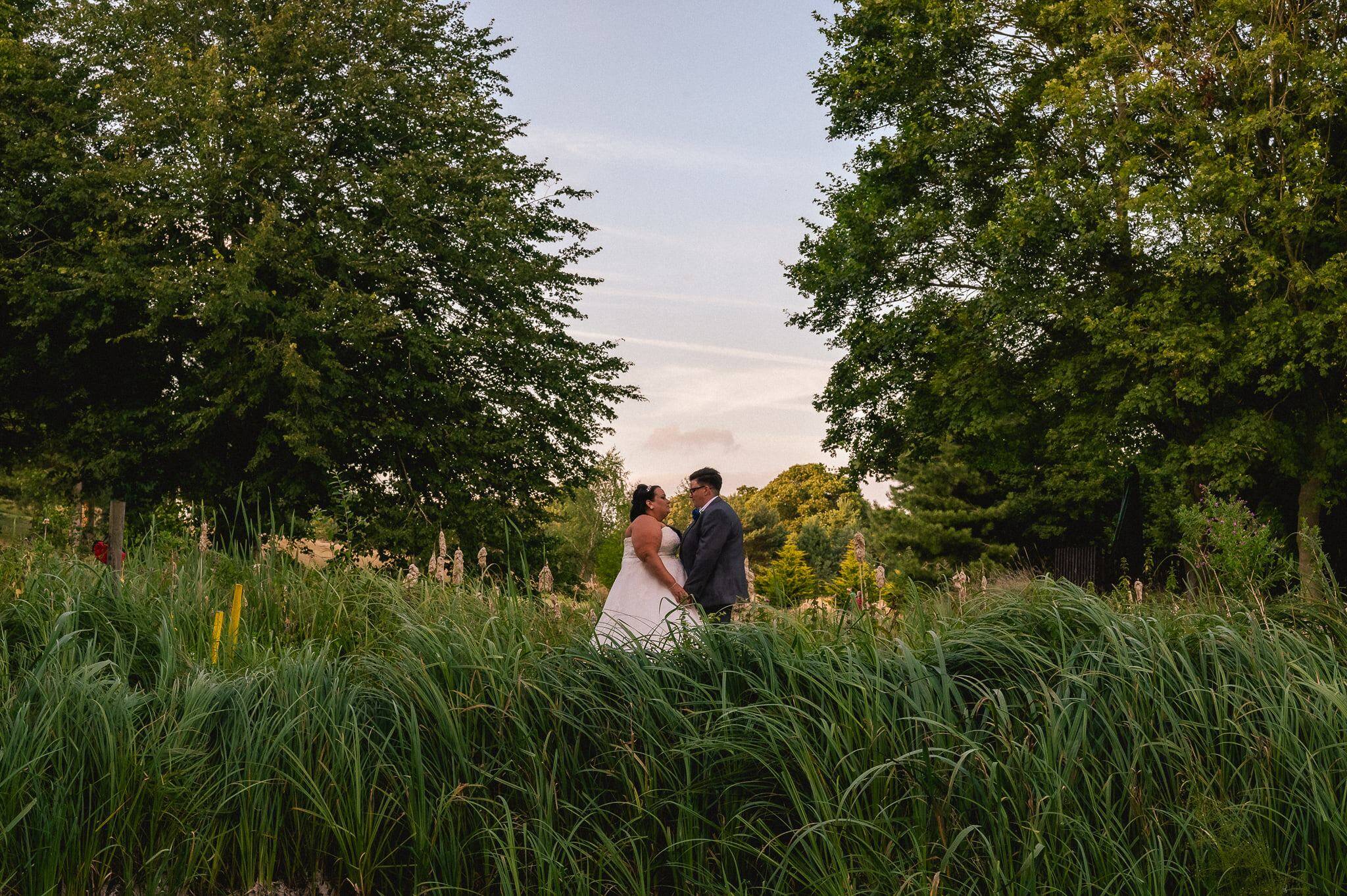Newly married couple walking together through a Norfolk landscape