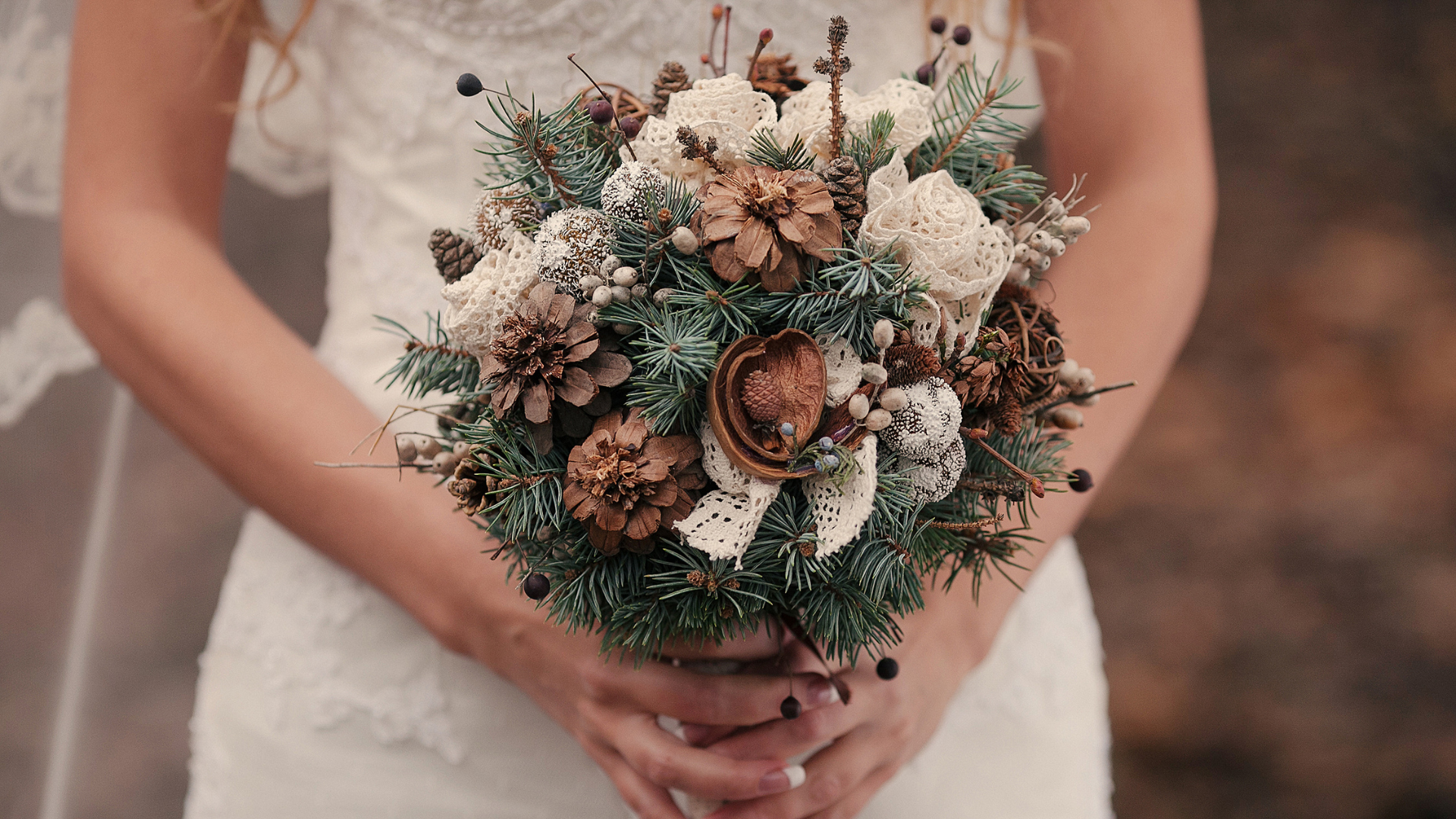 Winter wedding bouquet with evergreen foliage, pine cones and soft neutral flowers