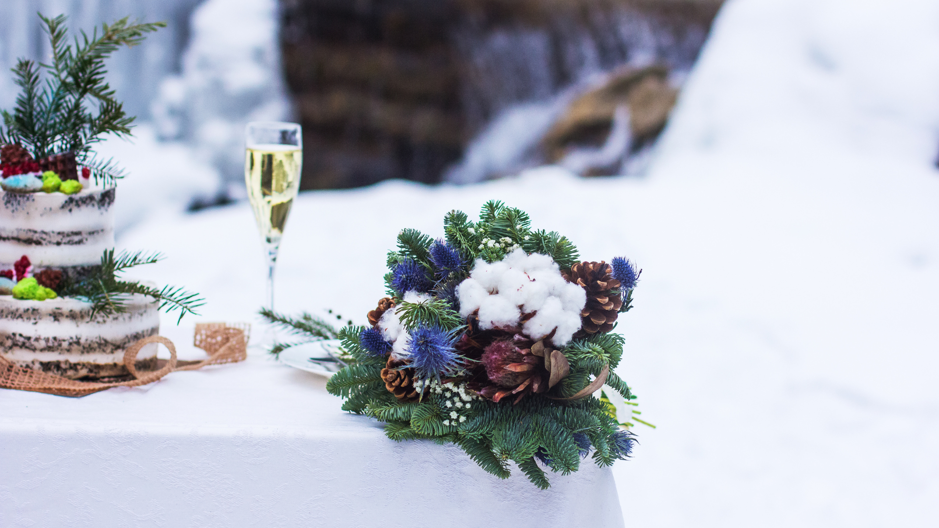 Winter wedding cake and bouquet with evergreen foliage and snowy surroundings